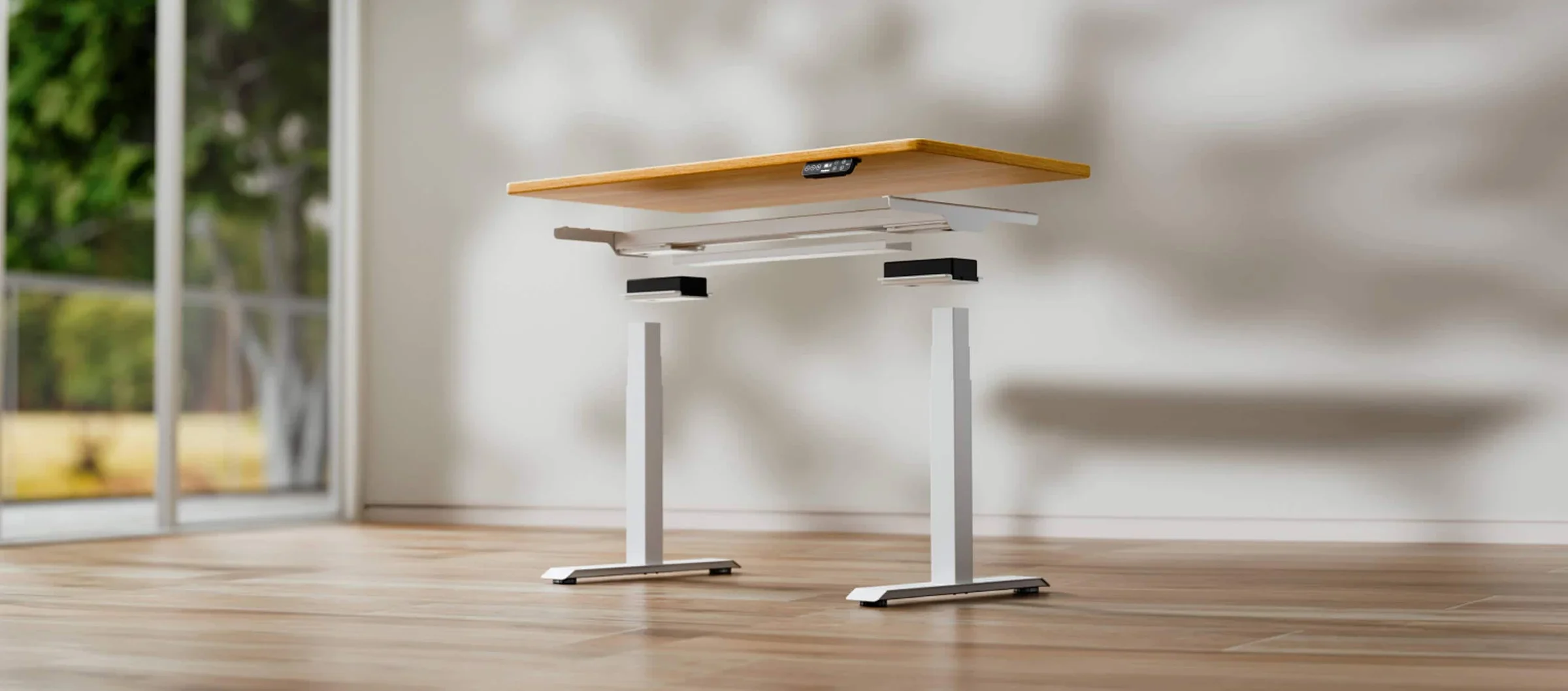 A white E7 frame shown in parts: the desktop floating above the crossbar, the motor housings and two legs, in a sunlit room.
